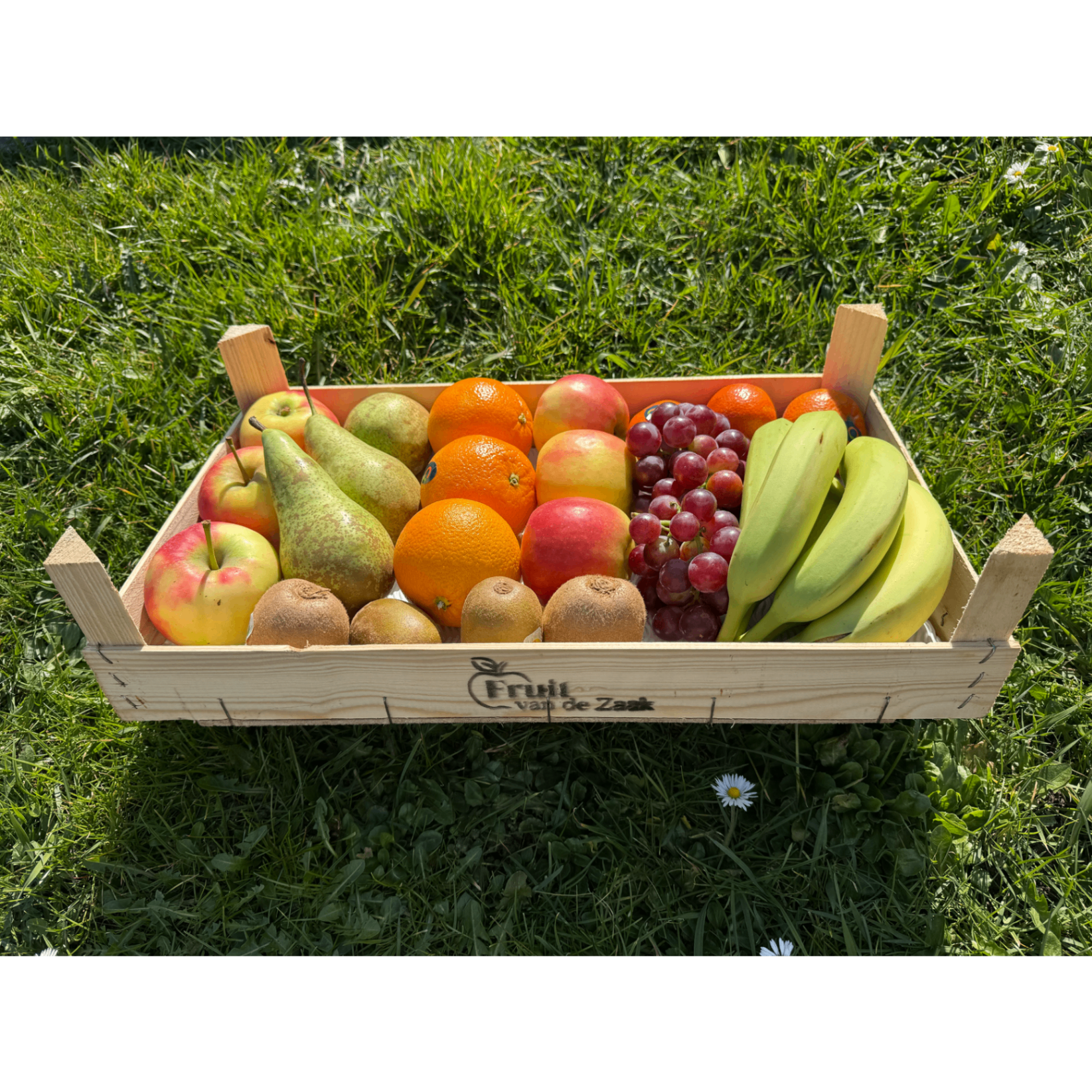 Houten kist met vers fruit in het gras